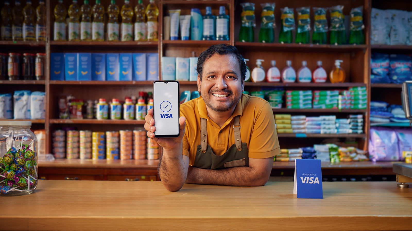 Hombre sonriente sosteneniendo su celular en su comercio